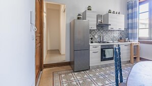 Eine kleine Küche mit Kühlschrank, Herd und Schränken.