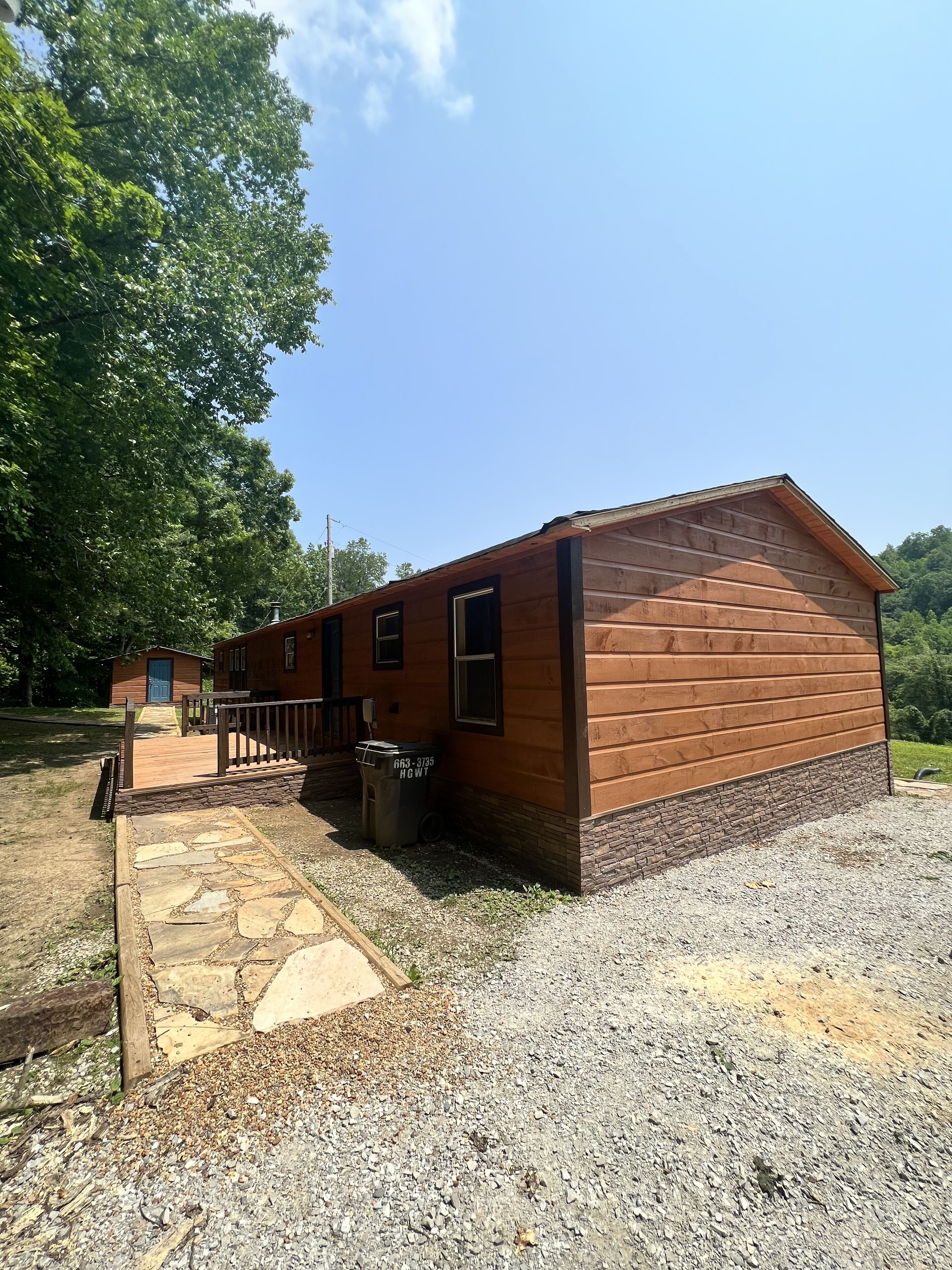 A wooden cabin with a stone pathway leading to a wooden deck.