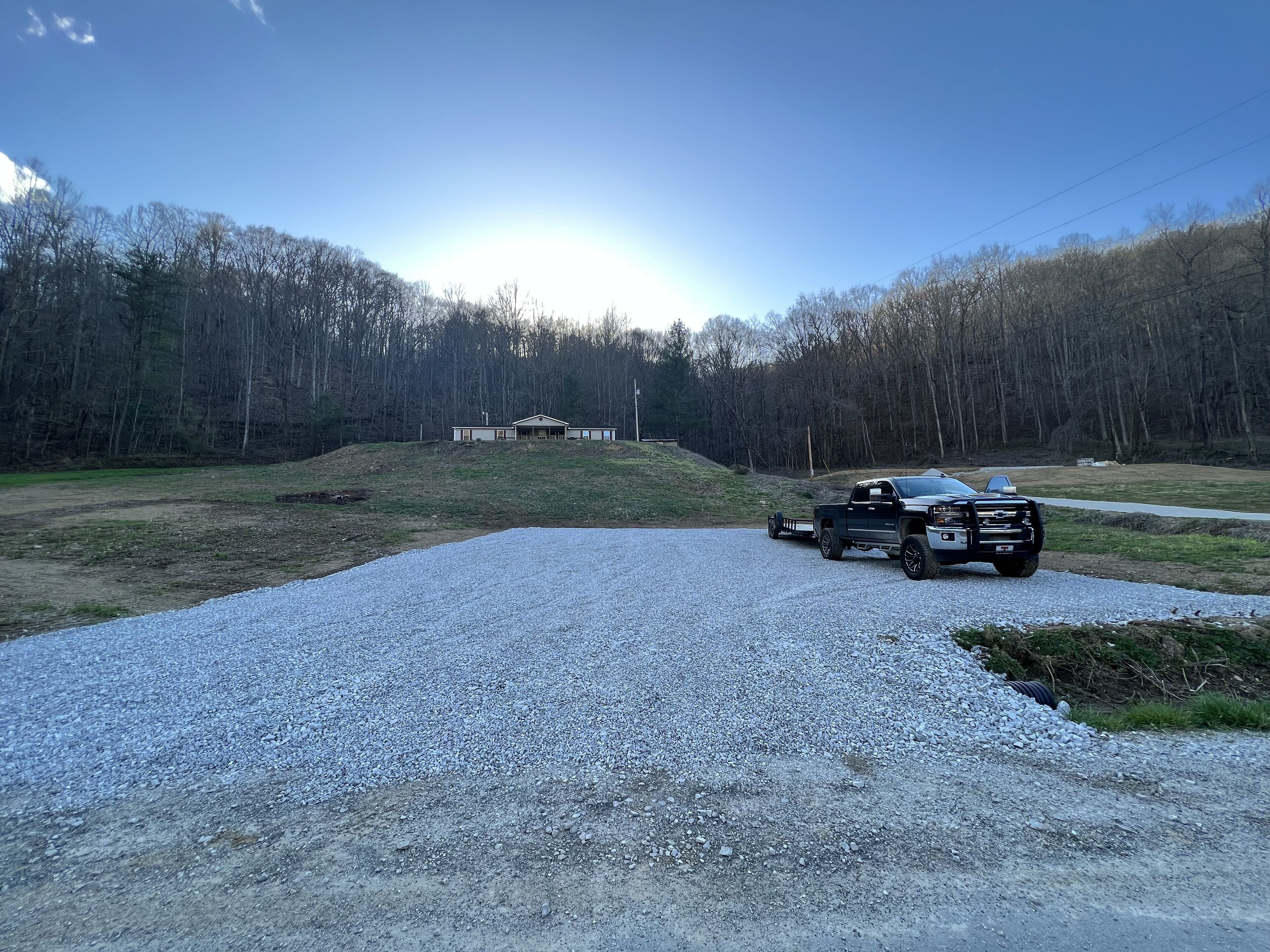 A gravel driveway leading to a house with a garage, surrounded by a forested area.