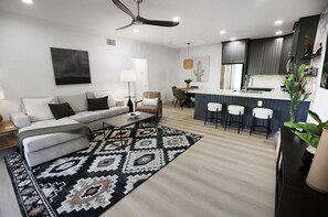 Relax in this stylish living space with a sofa set, dining table, and kitchen bar.