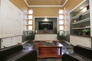 Relax in this inviting living room with a central coffee table and comfortable seating, a large flat-screen TV, and shelving units.