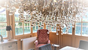 A dining area with a patterned chair, a table, and a chandelier with hanging light bulbs. - Vacation apartment Sonnenblick Deluxe ground floor (Reit im Winkl)