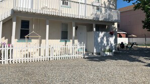 A two-story building with a white picket fence, a balcony, and a gravel driveway.