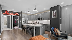 A modern kitchen with a central island, grey cabinets, and pendant lighting. - The Tiger Den - Hottub -Rooftop- Gameroom (Nashville)