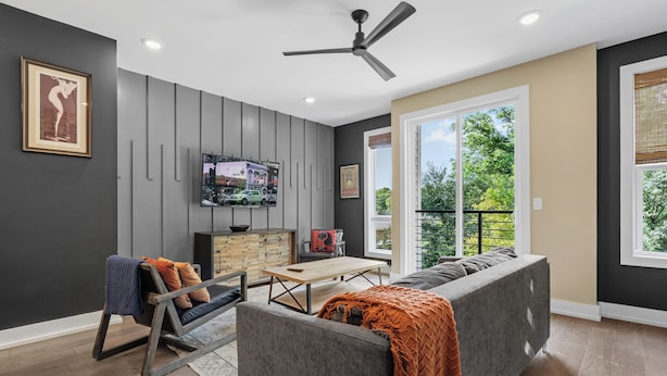 A modern living room with a sofa, a wooden coffee table, and a television on the wall. - The Tiger Den - Hottub -Rooftop- Gameroom (Nashville)