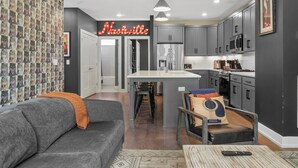 A modern kitchen with grey cabinets, a central island, and a neon sign reading "Nashville". - The Tiger Den - Hottub -Rooftop- Gameroom (Nashville)