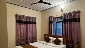 Un dormitorio con cama, cortinas, ventilador de techo y ventana con contraventanas.