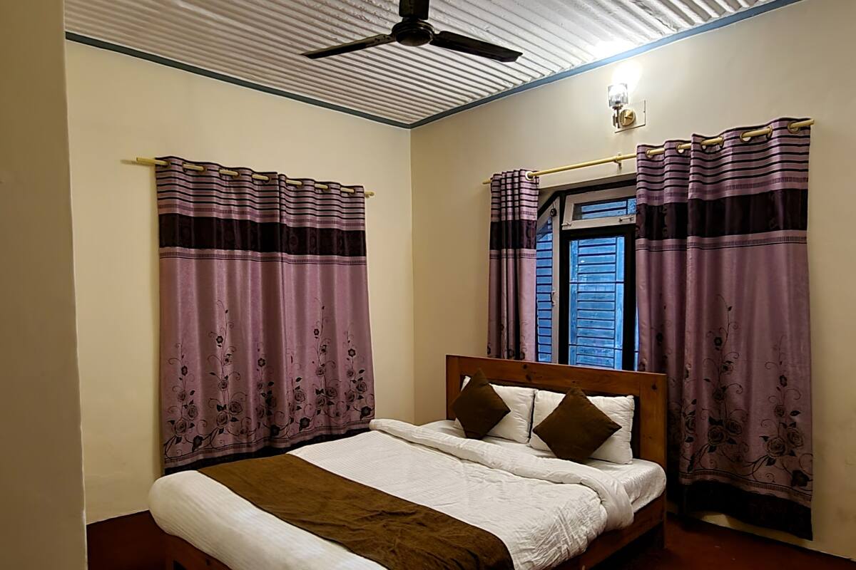 A bedroom with a bed, curtains, a ceiling fan, and a window with shutters.