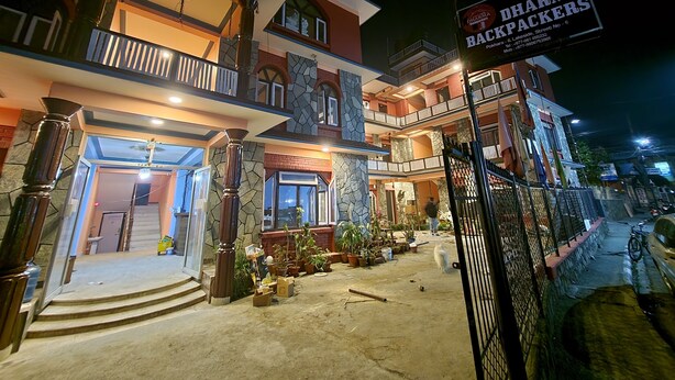 Un edificio de varios pisos con un letrero que dice 'Dharma Backpackers' en la planta baja.