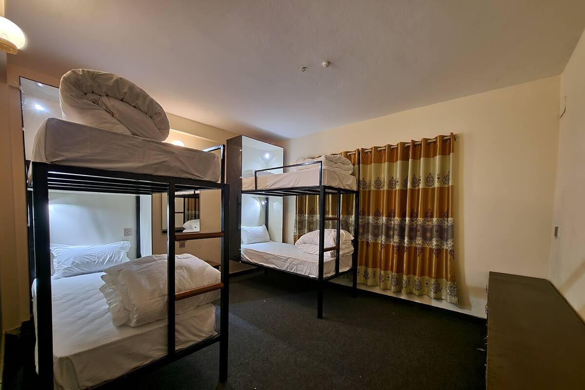 A room with bunk beds, a mirror, a curtain, and a small table.