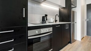A modern kitchen with black cabinetry, a stainless steel range, a built-in oven, a coffee maker, and a toaster. - Relaxing City Center Studio Close to Queen St (Auckland)
