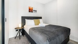 A hotel room with a bed, a bedside table with a lamp, and two wall-mounted pictures. - Relaxing City Center Studio Close to Queen St (Auckland)