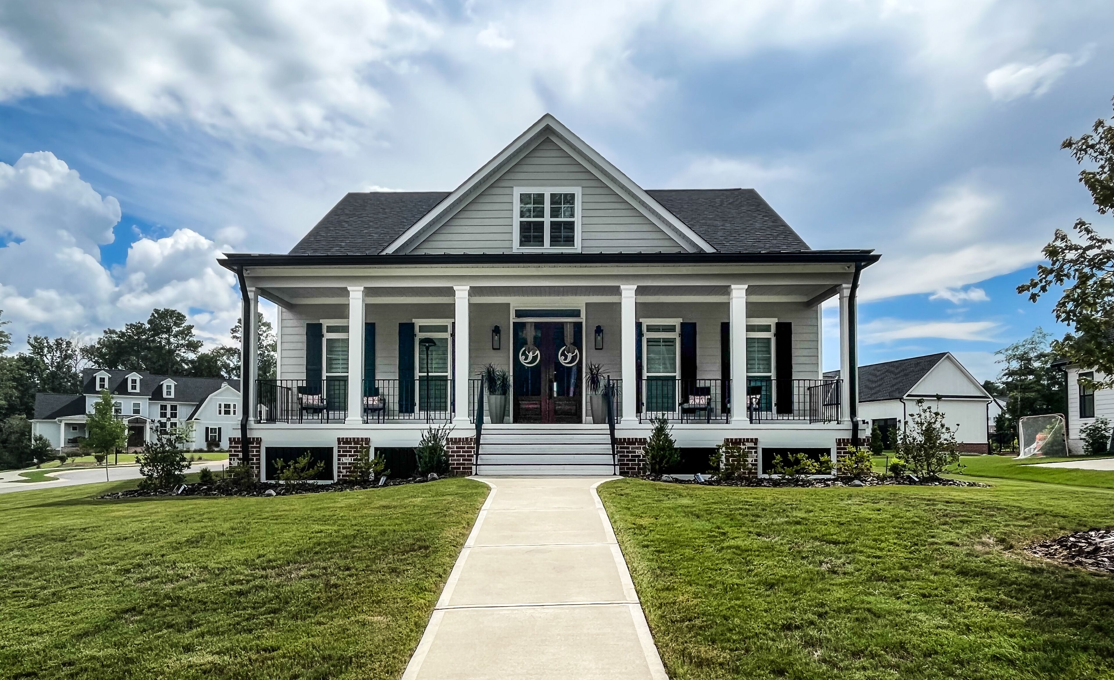 A two-story house with a front porch, a driveway, and a lawn.