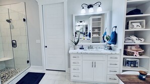Une salle de bain moderne avec une douche à parois de verre, un meuble-lavabo avec un miroir et des étagères intégrées.