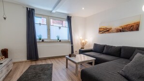 Un salon moderne avec un canapé gris, une table basse et une grande fenêtre agrémentée de rideaux.