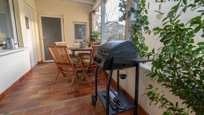 Une terrasse avec un barbecue, des chaises et une table.