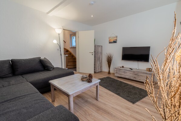 A modern living room with a sectional sofa, a coffee table, a TV, and a staircase leading to an upper level.