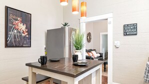 A modern kitchen with a wooden island, pendant lights, a framed menu, and a motivational sign.