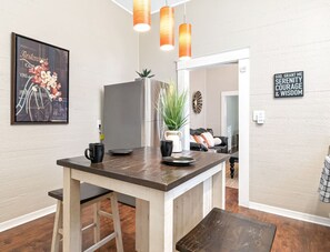 A modern kitchen with a wooden island, pendant lights, a framed menu, and a motivational quote on the wall.