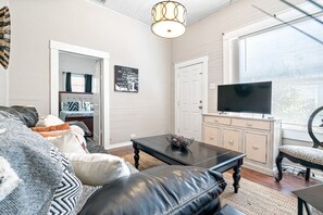 Een woonkamer met een bank, een salontafel, een televisie en een deur.