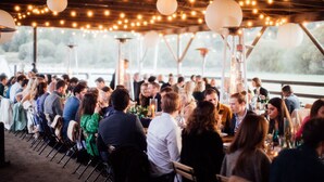 An outdoor event with people seated at tables under string lights and paper lanterns. - Saturn's Return (Friday Harbor)