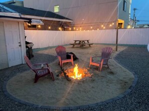 An outdoor patio with a fire pit, four Adirondack chairs, and string lights. - Apts 3&4 | Steps to Boardwalk w/ Parking & Grill (Seaside Heights)