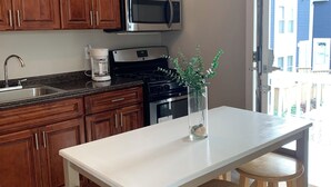 Una cocina moderna con armarios de madera, microondas de acero inoxidable, cafetera y una isla grande con taburetes.