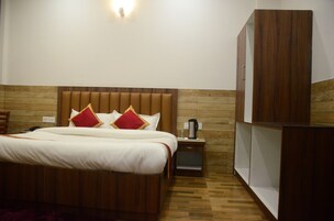 A neatly made bed with a wooden headboard, a bedside table with a lamp, and a wardrobe.