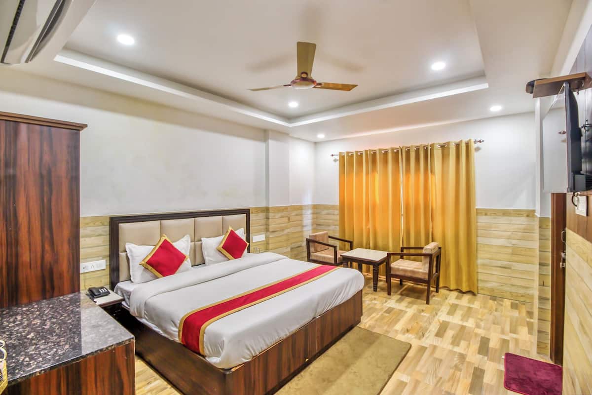 A hotel room with a bed, bedside table, desk, chair, and a ceiling fan.