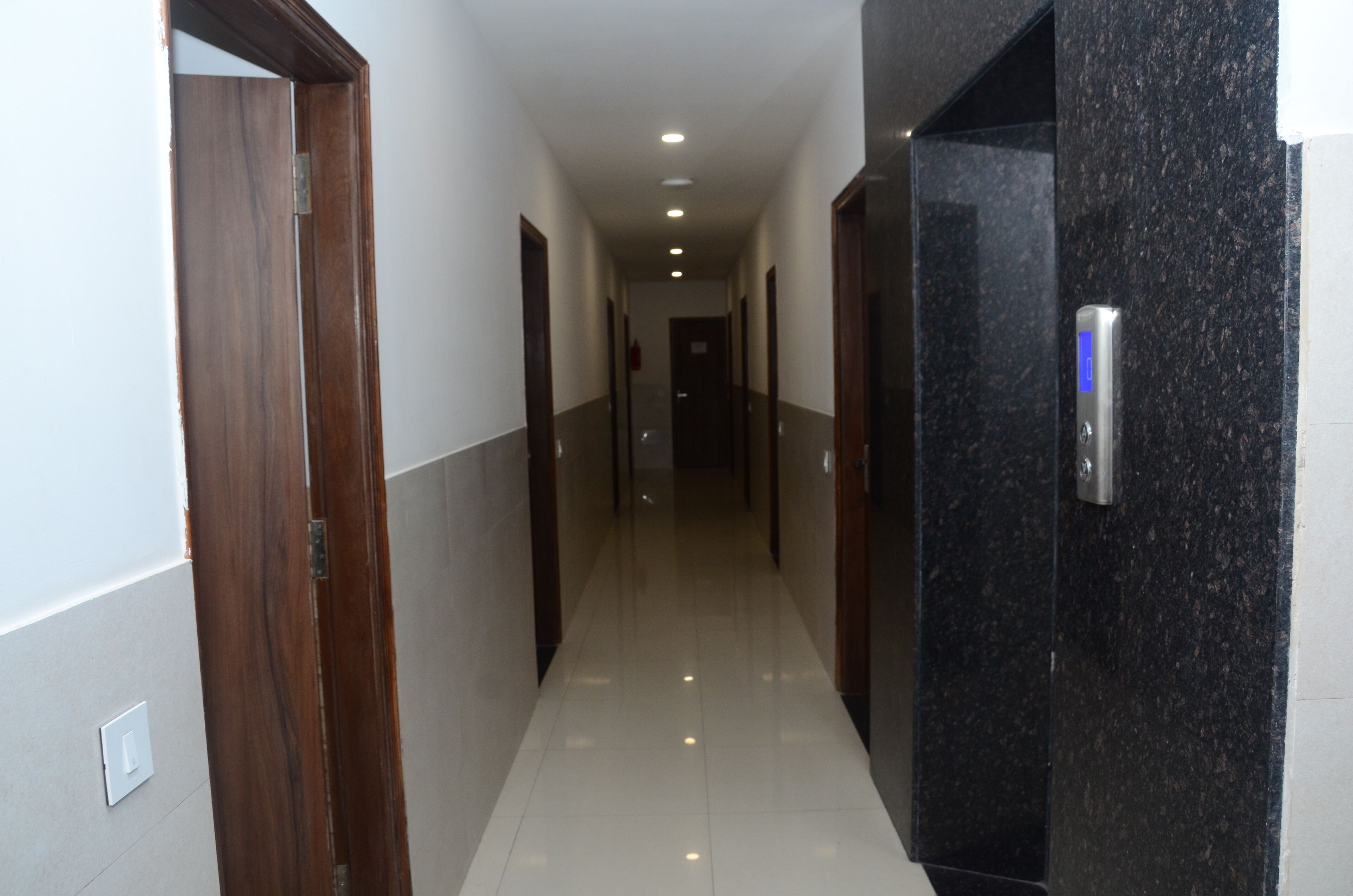 A hallway with wooden doors and a black marble wall.