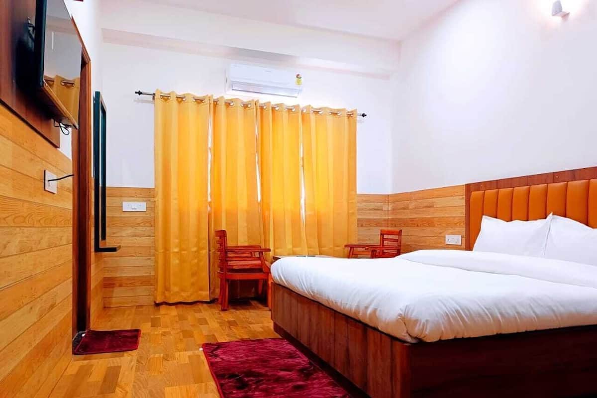 A hotel room with a wooden floor, a bed with white bedding, a red rug, a wooden chair, and a yellow curtain.