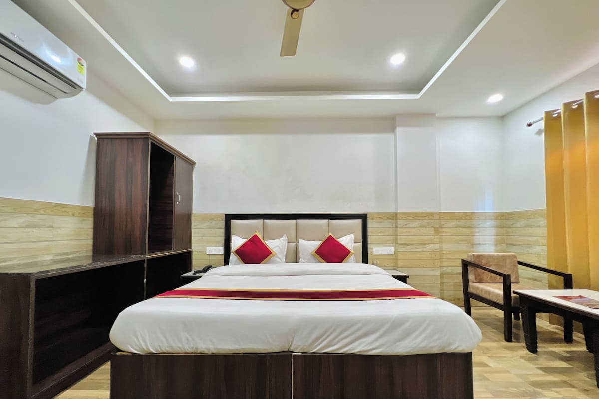 A hotel room with a large bed, a wardrobe, a desk, and a chair.
