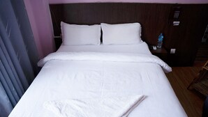 Un lit bien fait, avec du linge de lit blanc, dans une chambre d'hôtel.