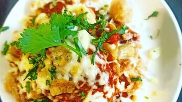 Uma tigela de nachos cobertos de queijo, tomate e coentro.