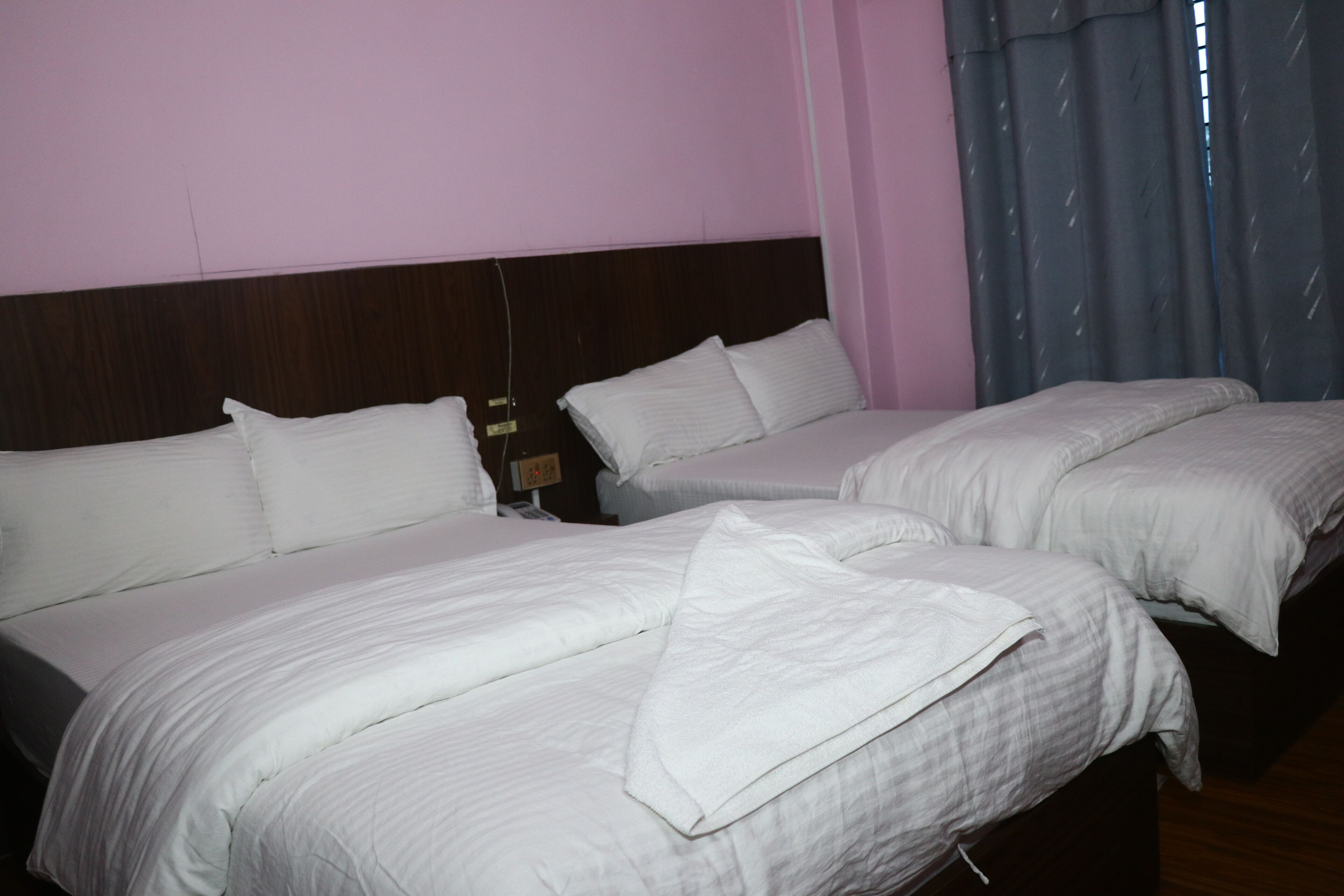 A hotel room with two beds, a wooden headboard, and a window with curtains.