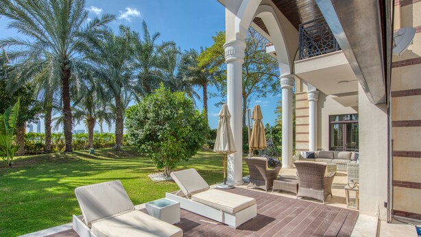 A patio area with lounge chairs, a small table, and umbrellas. - Maison Privee - Majestic Resort Villa with Private Pool on The Palm (Dubai)