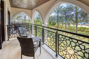 Un balcon avec vue sur des palmiers et un bâtiment situé au loin.