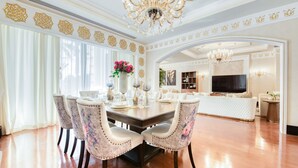 A dining area with a wooden table, floral upholstered chairs, and a chandelier. - Maison Privee - Majestic Resort Villa with Private Pool on The Palm (Dubai)