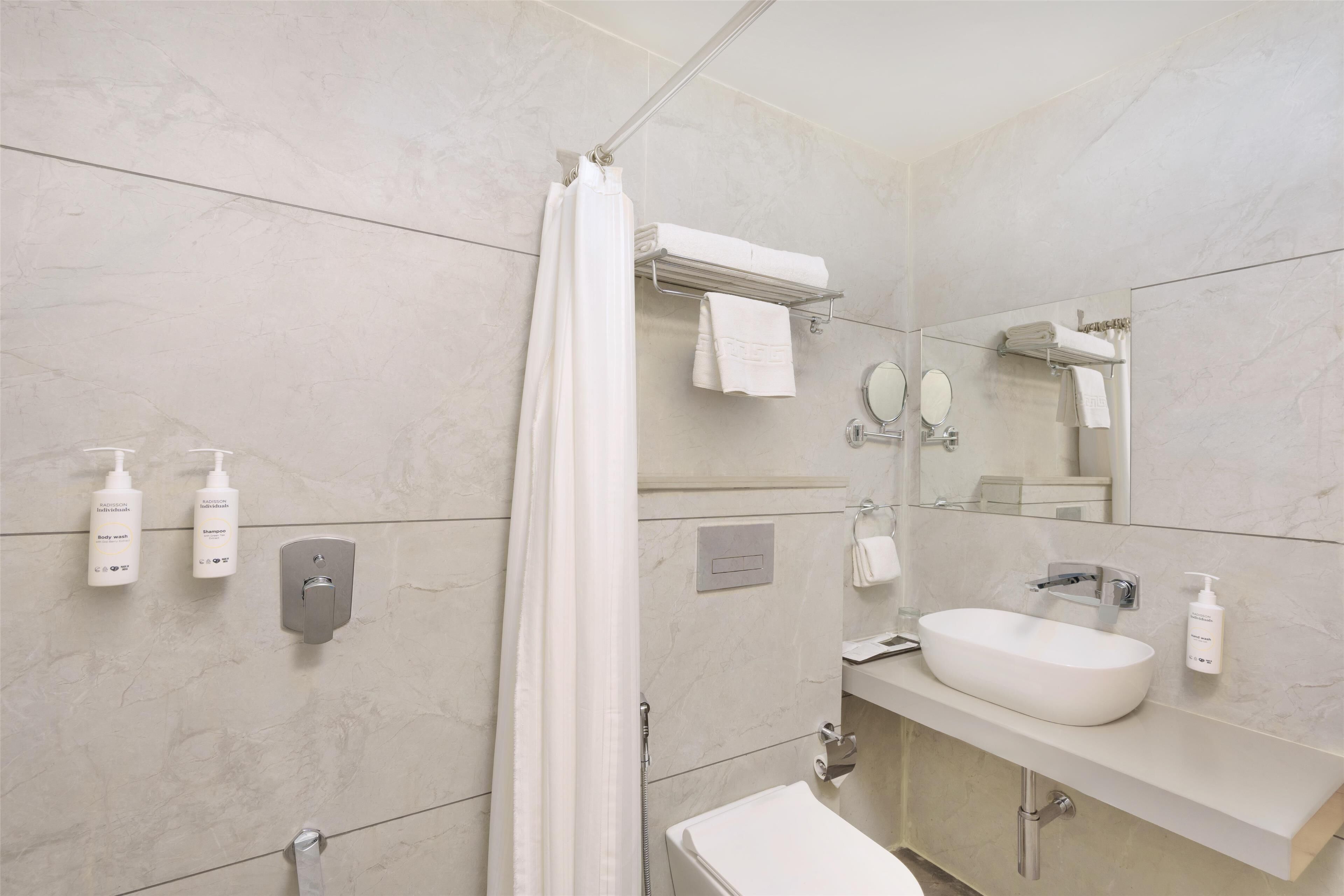 A modern bathroom with a shower, a sink, and a mirror.
