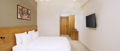 A modern hotel room with a large bed, a ceiling fan, a flat-screen TV, and a wooden headboard.