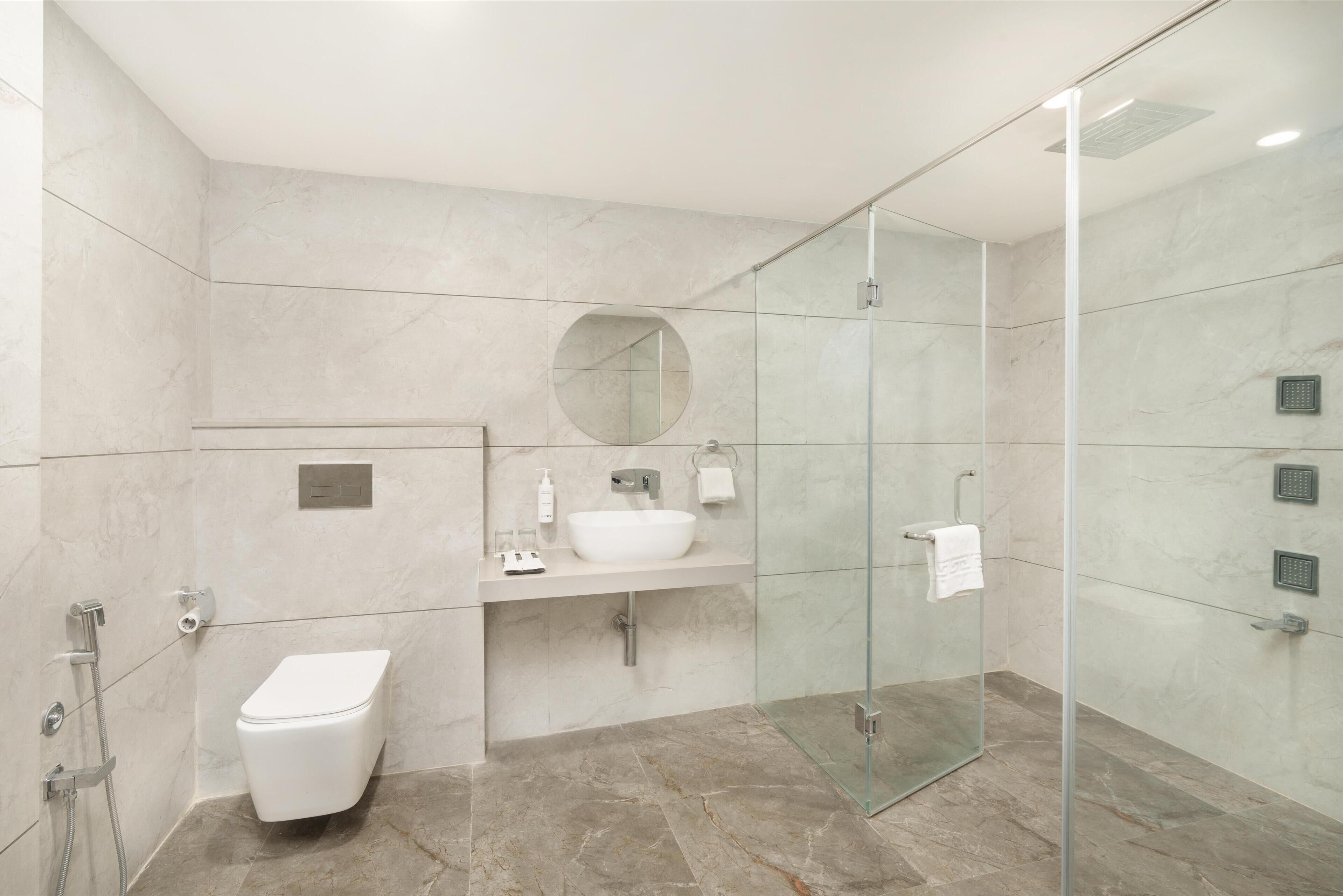 Un bagno moderno con cabina doccia in vetro, lavabo bianco e water.