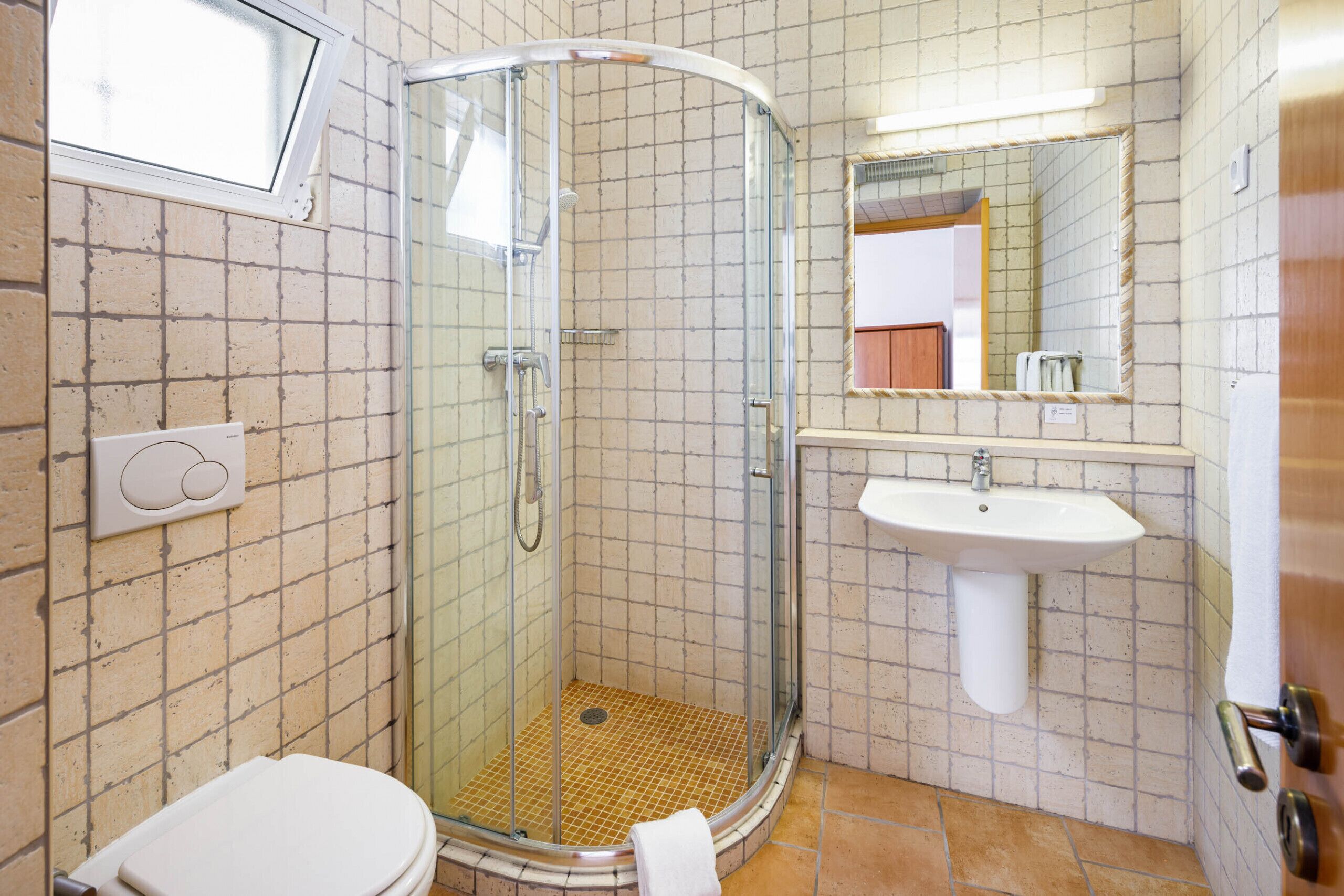 A bathroom with a glass-enclosed shower, a white sink, and a toilet.
