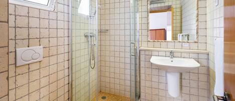 A bathroom with a glass-enclosed shower, a white sink, and a toilet.