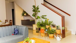 Un salon avec un canapé gris, une petite table et diverses plantes en pot.
