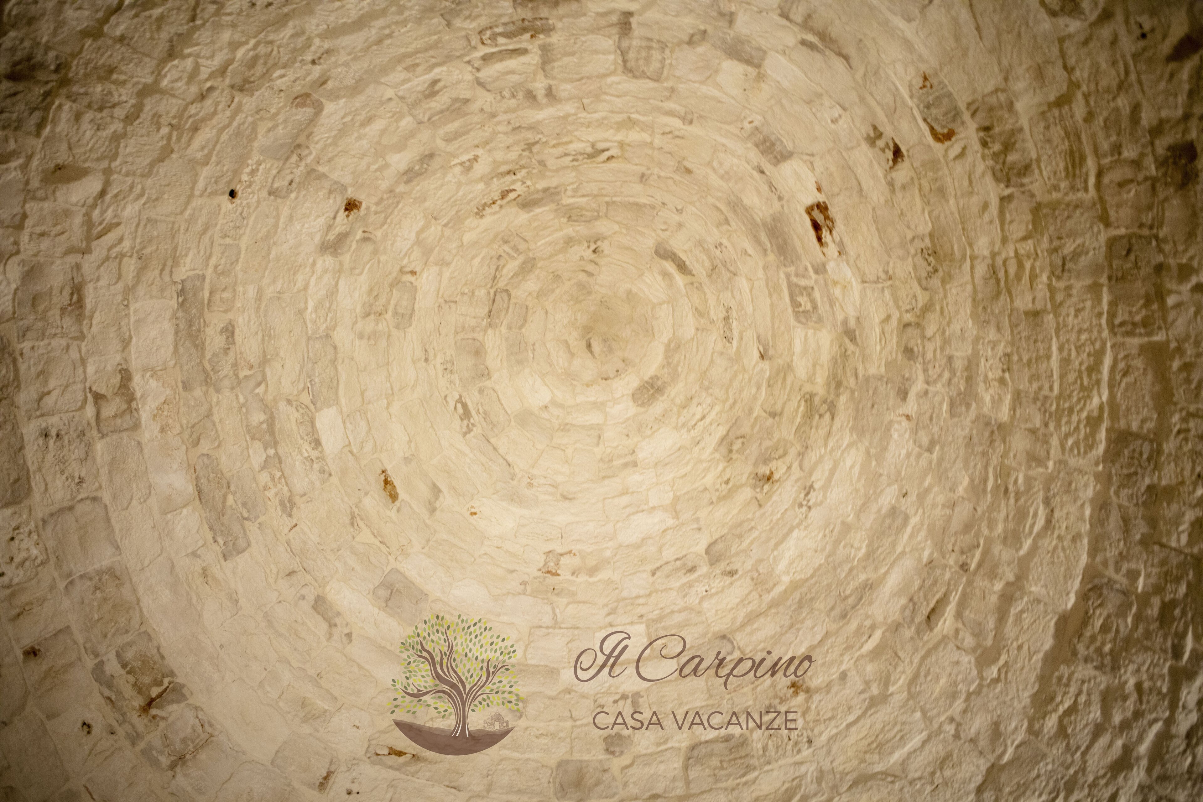 A circular stone wall with a logo and text at the bottom.