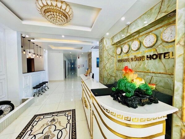 Eine Hotelrezeption mit Marmorwand, Uhren und einem Empfangstresen.