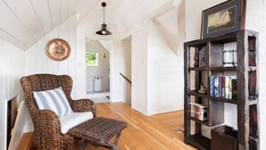 A cozy room with a wicker chair, a wooden bookshelf, and a ceiling fan. - NEWLY Renovated Anchor House | Rooftop Patio | Pet Friendly | 3min Walk to Beach (Freeland)