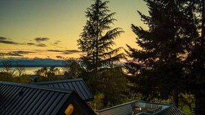 A modern house with a sloped roof, a glass balcony, and a view of the surrounding forest and mountains. - NEWLY Renovated Anchor House | Rooftop Patio | Pet Friendly | 3min Walk to Beach (Freeland)