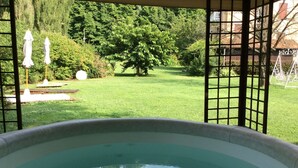 Uma banheira de hidromassagem com vista para um gramado bem cuidado e árvores.