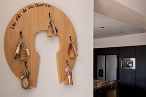 Eine Holzdeko-Wand mit Korken und Schlüsseln, und eine moderne Küche mit dunklen Schränken und Edelstahlgeräten.